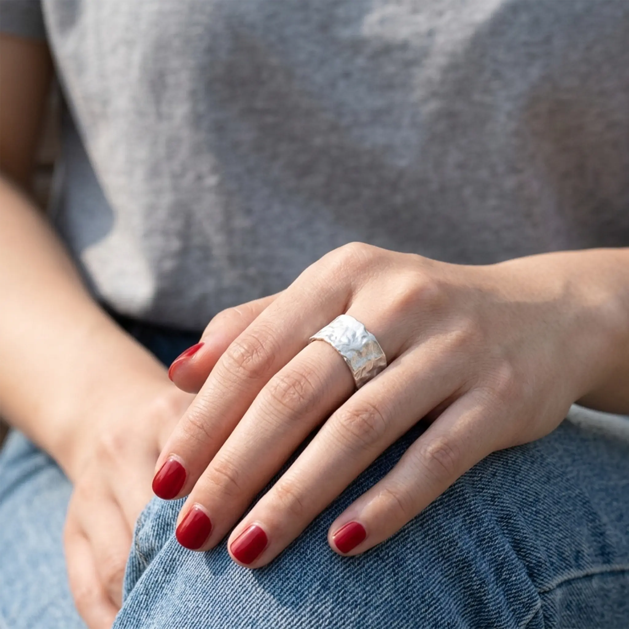 Handgefertigter Statement-Ring Silber breit und rustikal an Hand mit rotem Nagellack.