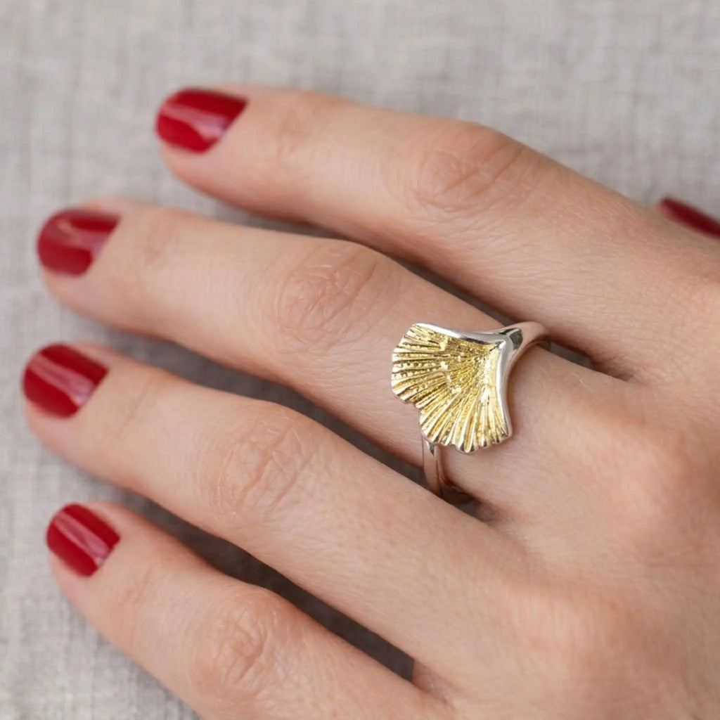 Nahaufnahme Hand mit roten Nägeln: Silberring mit vergoldetem Ginkgo-Blatt als Statement – moderner Damenring, filigranes Blattmotiv.