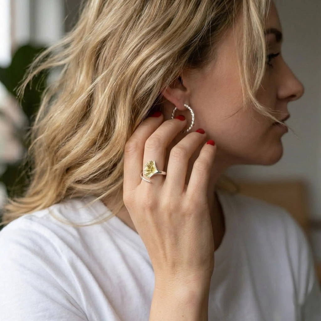 Profilaufnahme: blonde Frau berührt den Ohrring, roter Nagellack; Silberring mit vergoldetem Ginkgo-Blatt – stilvoller Damenring, moderner Look.