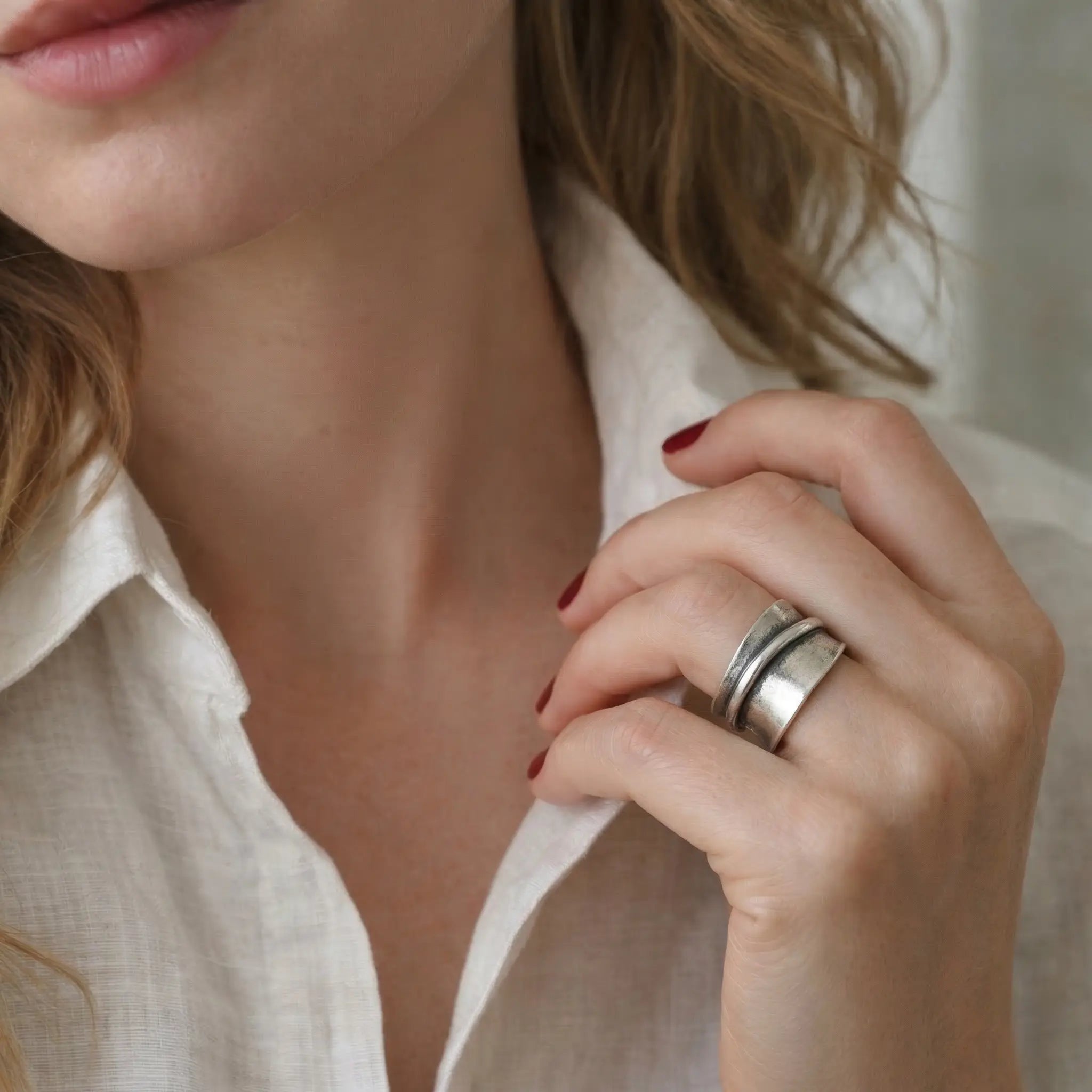 Breiter verstellbarer Silberring aus 925 Sterling Silber, moderner Damenring mit markantem Design, getragen an der Hand einer blonden Frau mit weißer Leinenbluse und rotem Nagellack