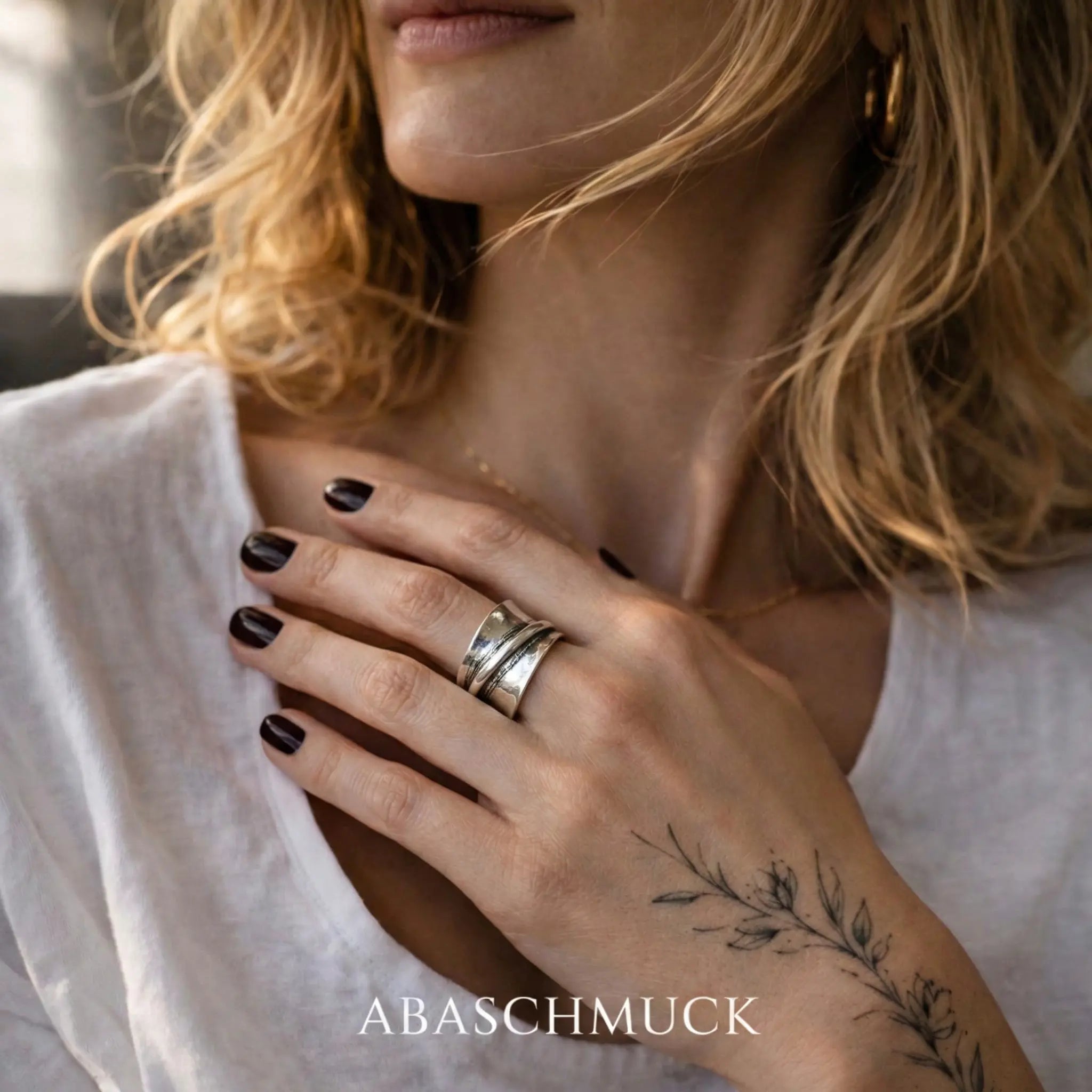 Breiter verstellbarer Silberring 925 für Damen, stilvoller Statement Ring mit modernem Design, getragen an der Hand einer blonden Frau mit botanischem Tattoo und schwarzem Nagellack