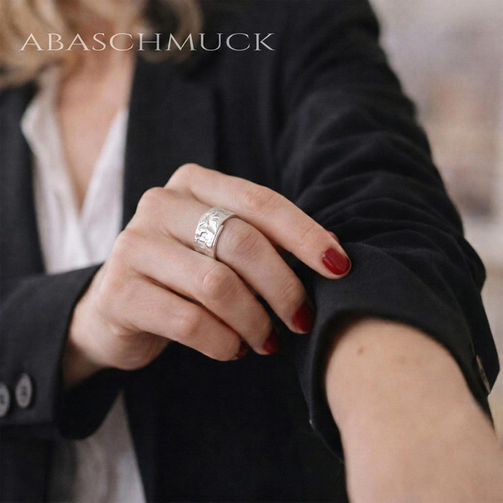 Damenhand mit rotem Nagellack am schwarzen Blazer, breiter 925 Sterling Silberring mit strukturierter Fläche, eleganter Statement Ring für moderne Business Looks
