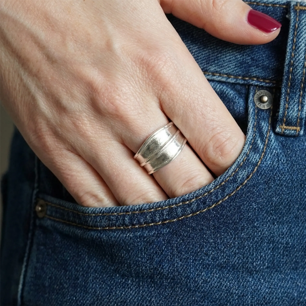 Detailaufnahme: breiter Silberring am Finger, Hand in der Jeanstasche, bordeauxrote Nägel, Casual-Style.