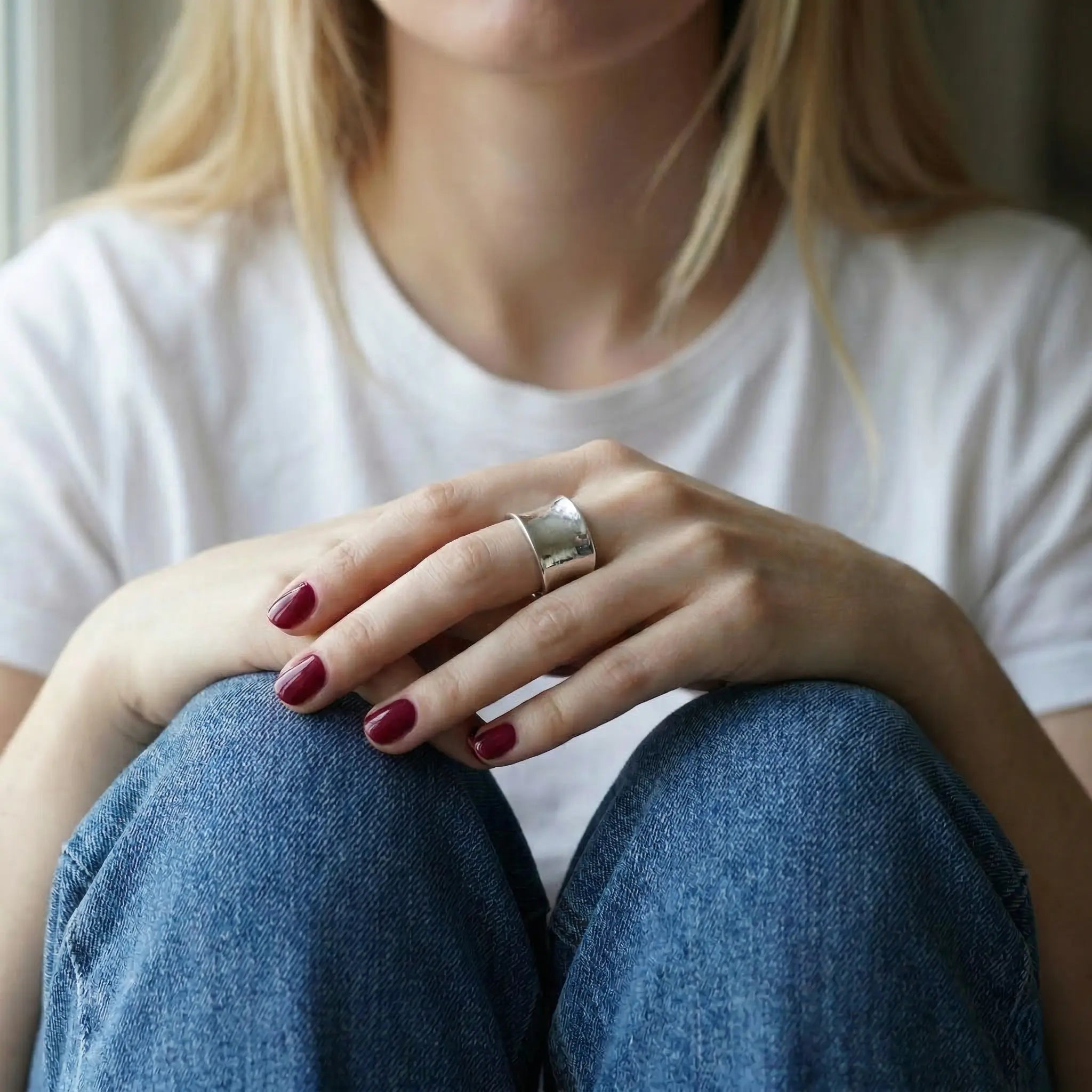 Verstellbarer breiter Silberring 925 für Damen, eleganter Statement Ring an der Hand einer blonden Frau mit rotem Nagellack, getragen zu weißem Shirt und Jeans im natürlichen Lifestyle Look