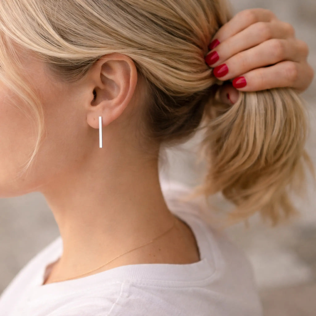 Moderne Silberohrringe 925 für Damen, minimalistische Stab Ohrringe aus Sterling Silber, eleganter Ohrschmuck an blonder Frau mit Pferdeschwanz und rotem Nagellack
