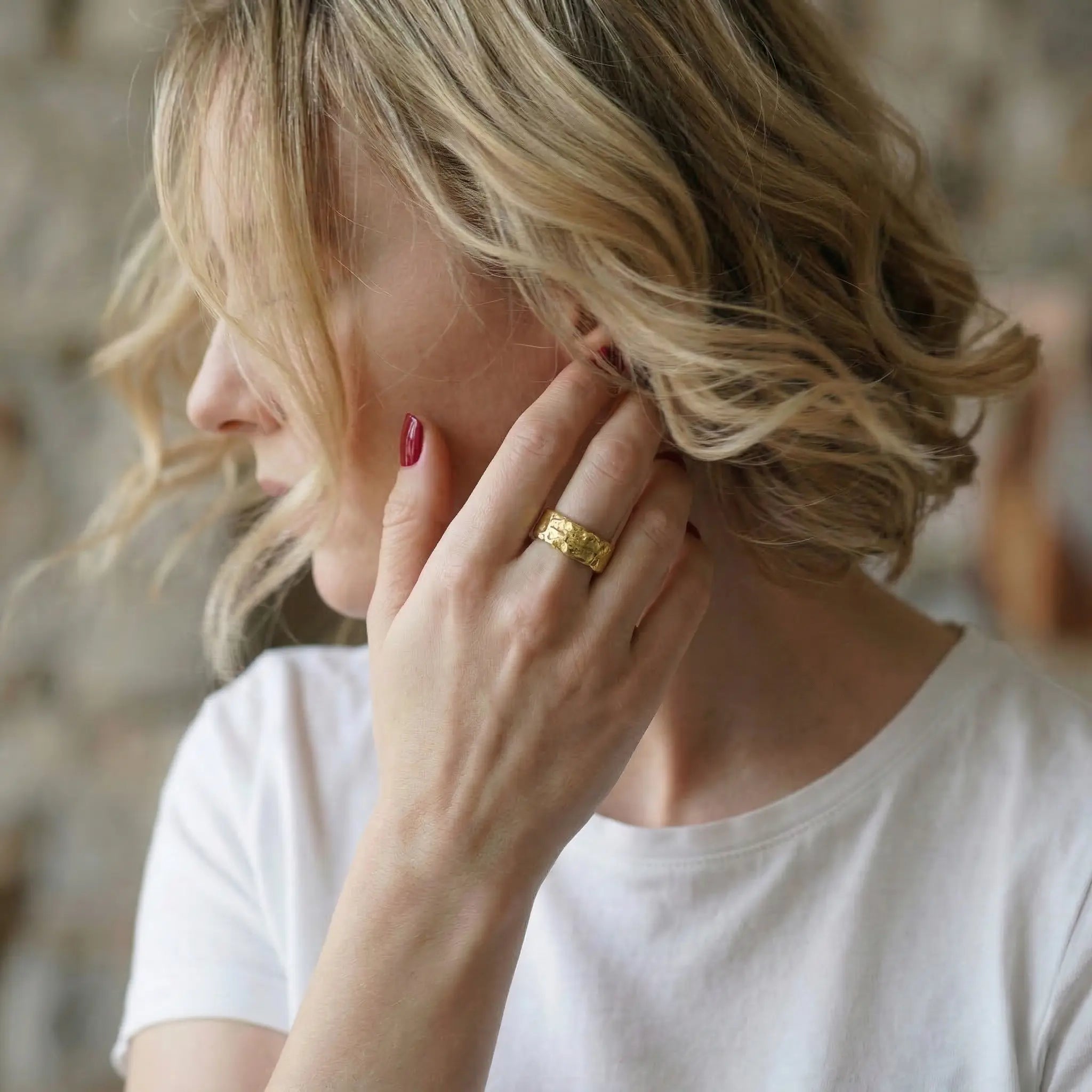 Vergoldeter Damenring aus 925 Sterling Silber mit markanter Struktur, eleganter Statement Ring an der Hand einer blonden Frau im natürlichen Lifestyle Portrait