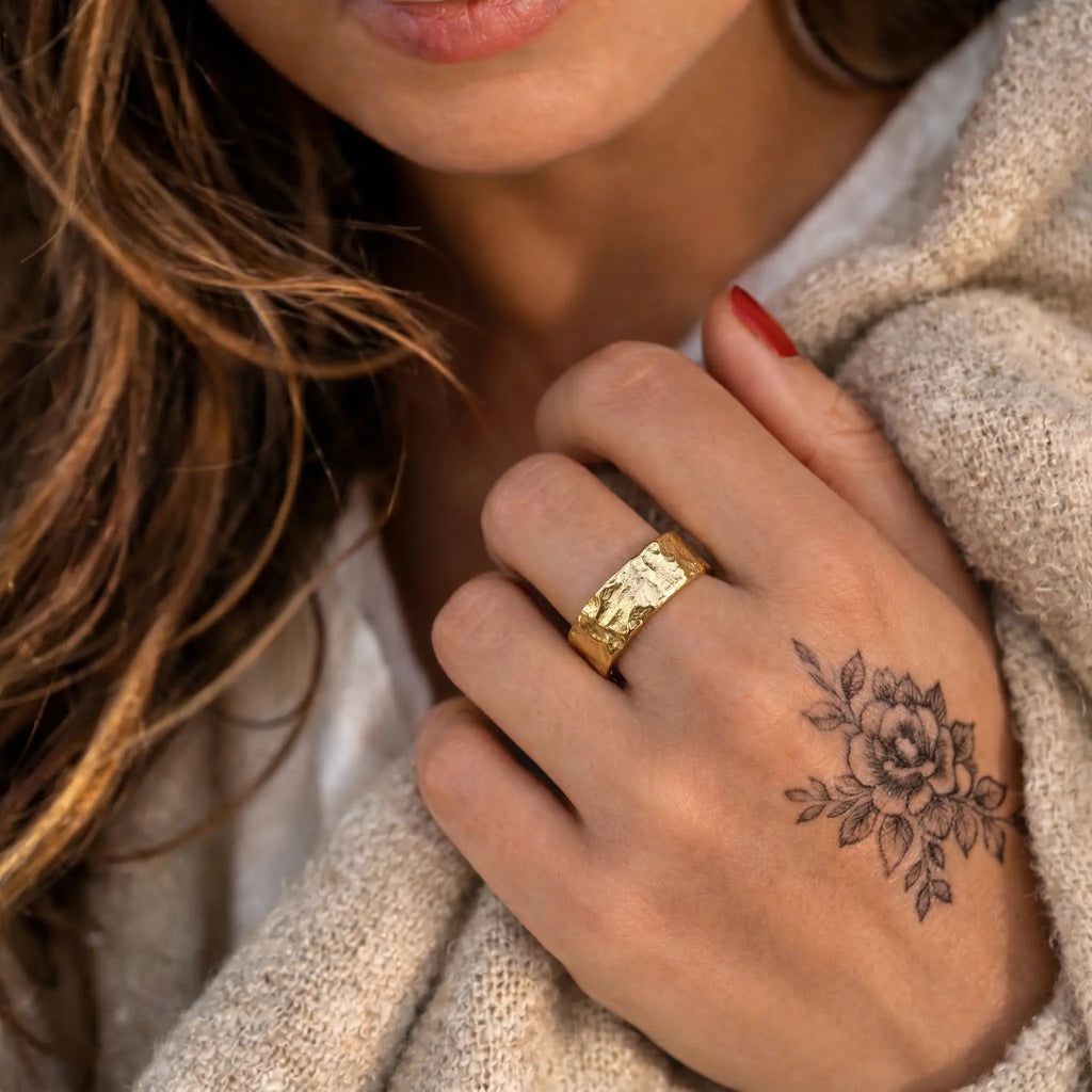 Breiter vergoldeter Silberring 925 für Damen, strukturierter Statement Ring mit glänzender Oberfläche, getragen zu hellem Strick und floralem Tattoo