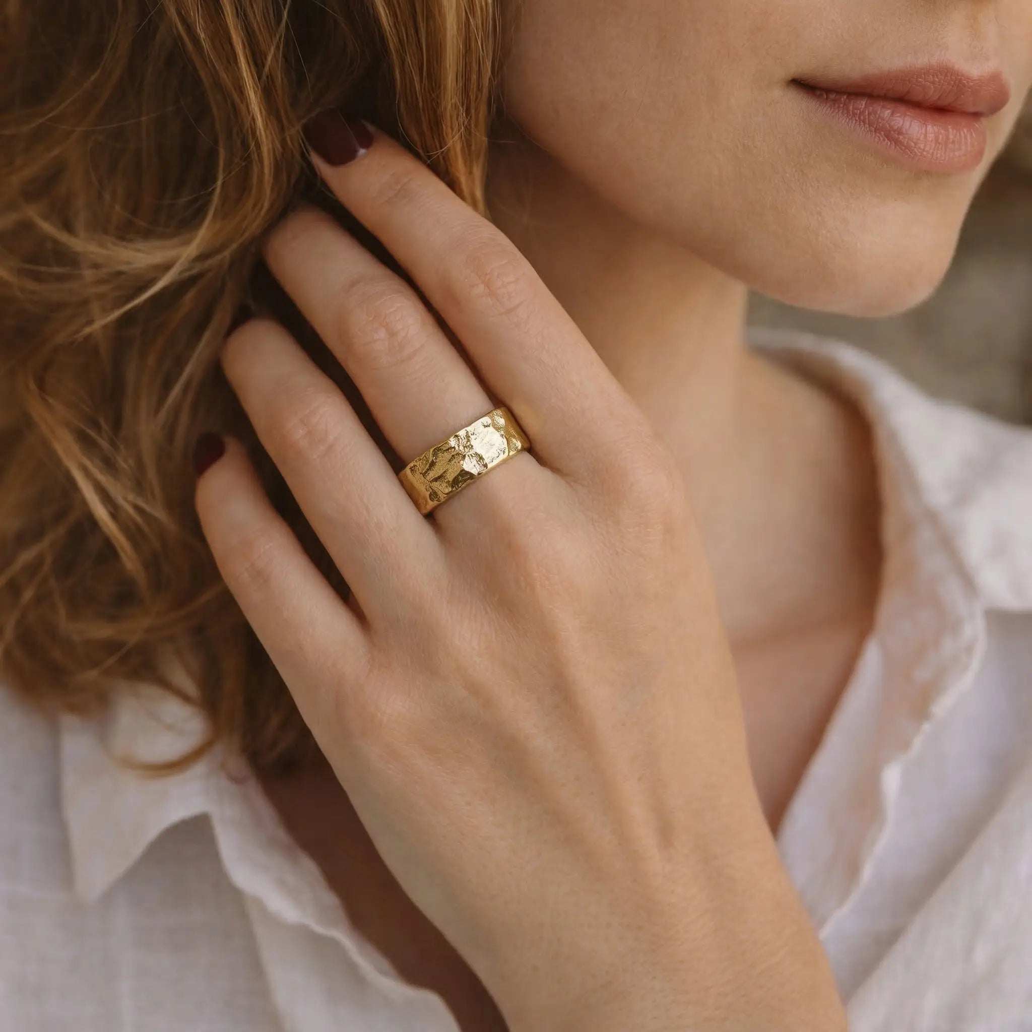Vergoldeter Statement Ring aus 925 Sterling Silber, breiter Damenring mit strukturierter Oberfläche, elegante Nahaufnahme an der Hand einer Frau mit weißer Bluse