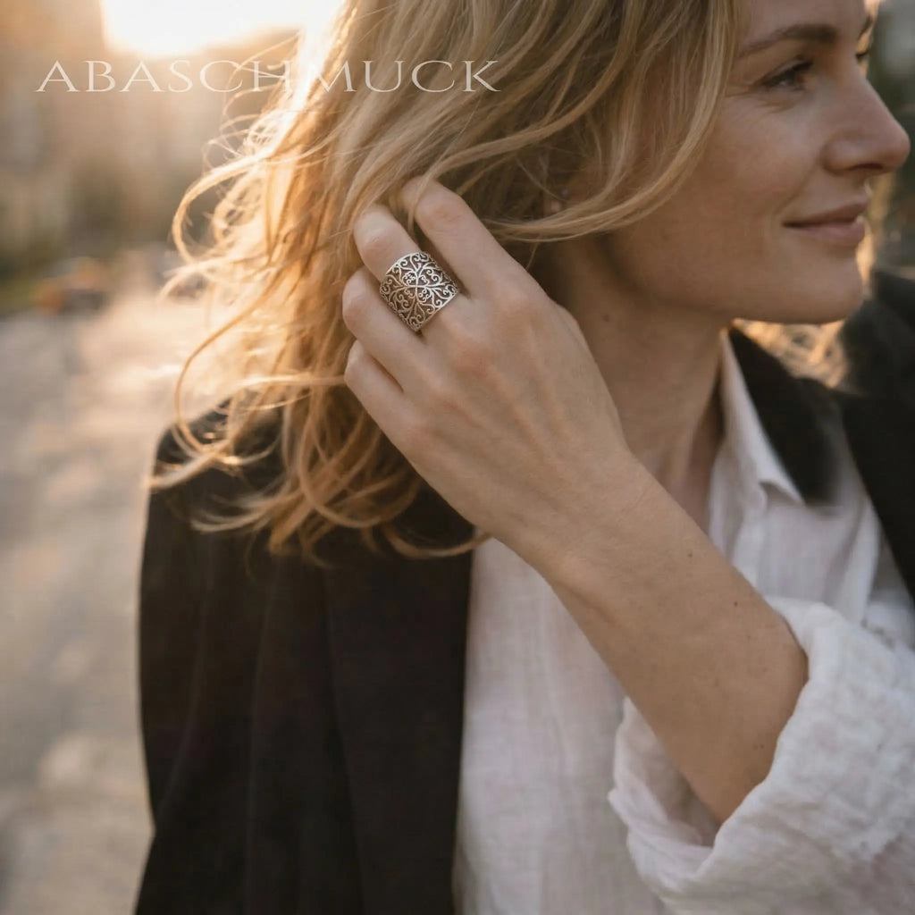 Blonde Frau mit großem verstellbarem Silberring aus 925 Sterling Silber mit ornamentalem Muster, Statement Ring Damen, getragen als eleganter Fingerring im warmen Abendlicht
