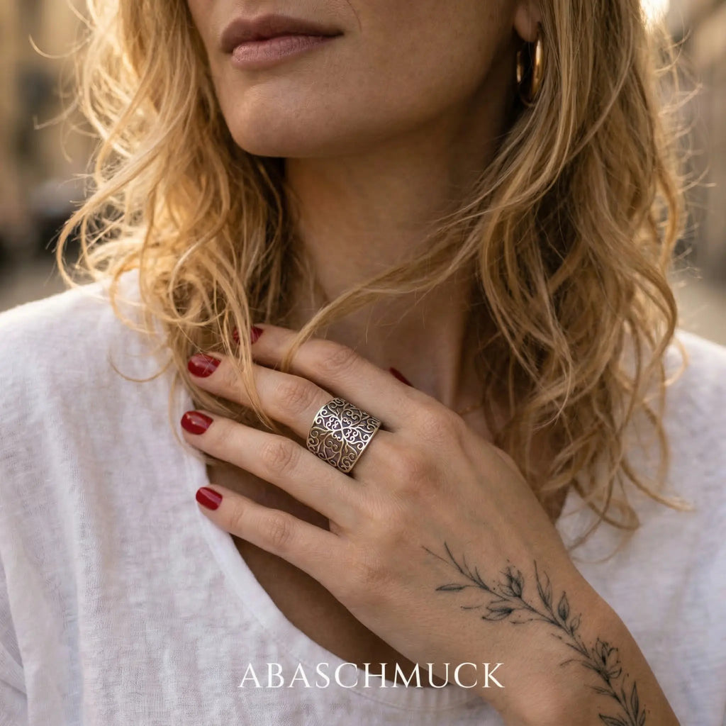 Großer Silberring aus 925 Sterling Silber mit filigranem Ornamentmuster an der Hand einer blonden Frau, Damen Statement Ring, verstellbarer Silberring im natürlichen Lifestyle Look