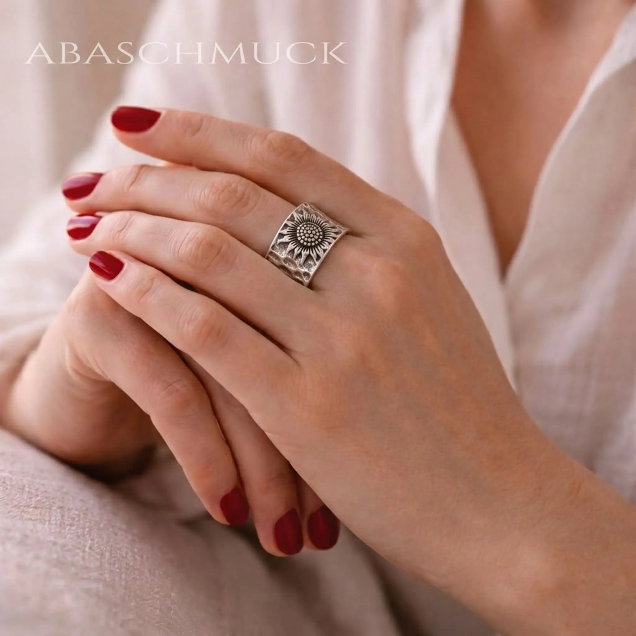 Detailaufnahme massiver 925 Sterling Silber Ring mit Sonnenblumen-Design und gehämmerter Optik auf gepflegten Händen.