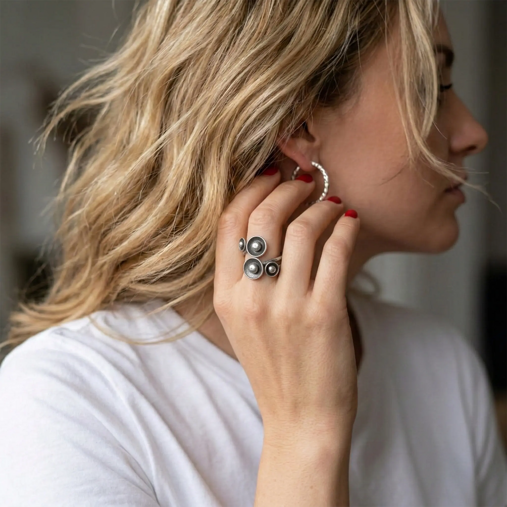 Moderner Silberring aus 925 Sterling Silber mit markantem Kugeldesign, verstellbarer Statement Ring an der Hand einer blonden Frau mit silberner Creole und weißem Shirt