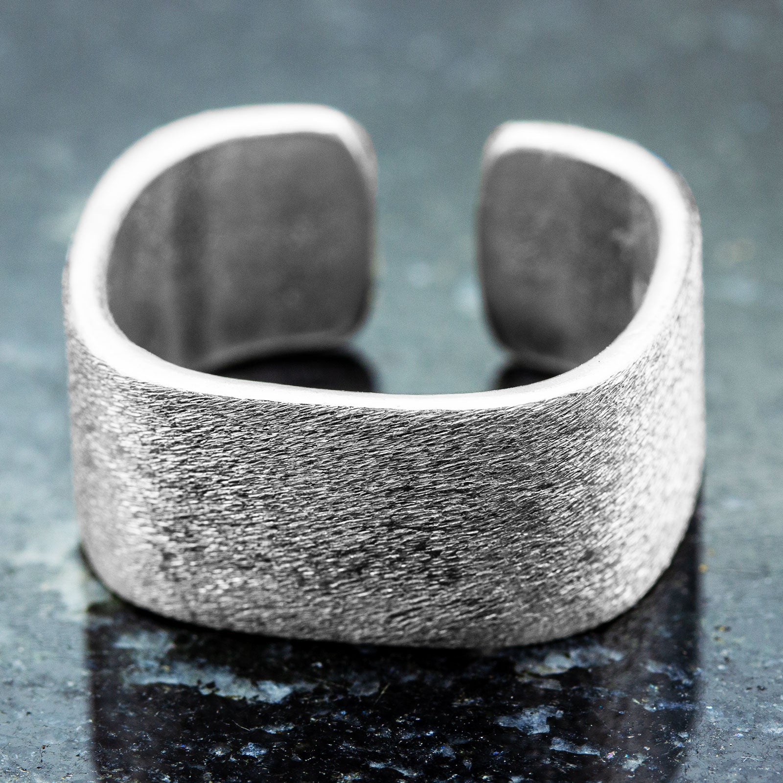 Verstellbarer mattierter Silberring 925 mit breiter Ringschiene auf dunkler Steinoberfläche