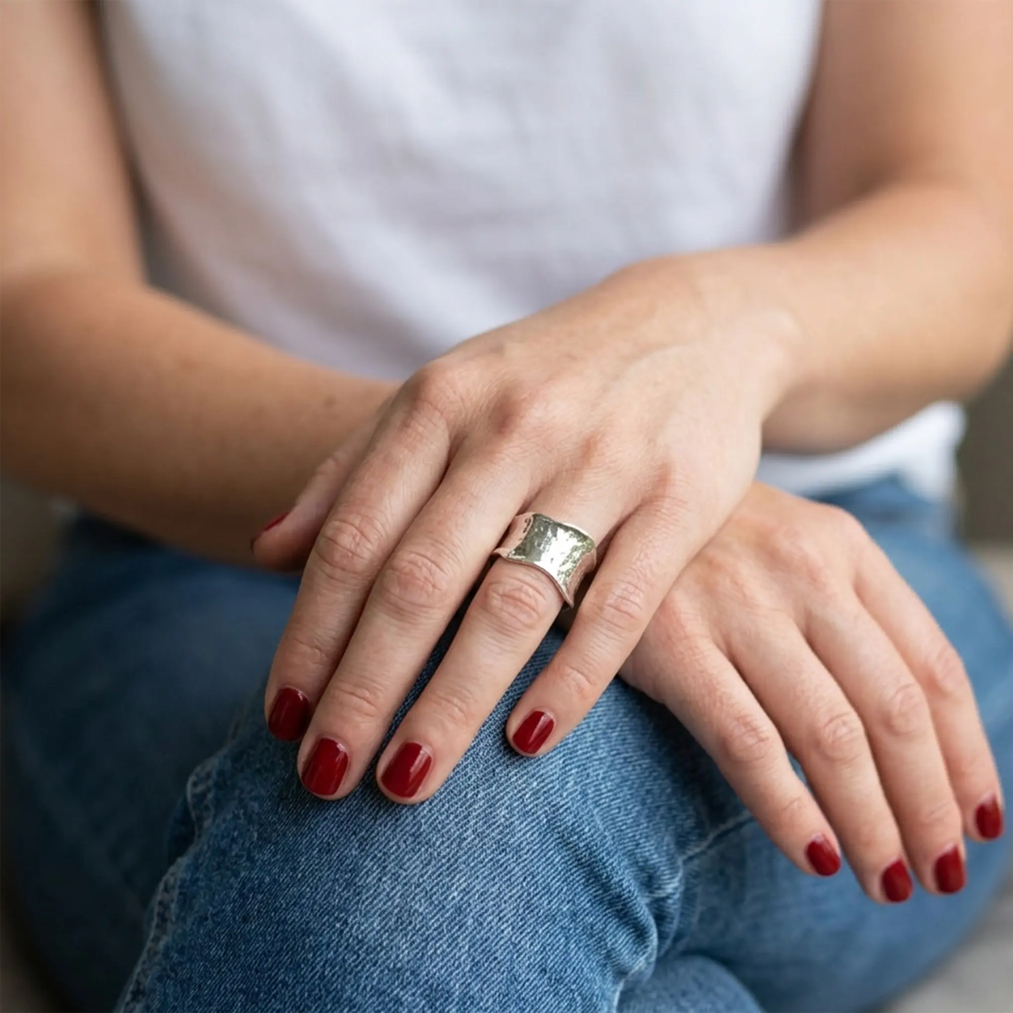 Handgefertigter Statement Ring Silber breit und gewölbt auf den Händen einer Frau.