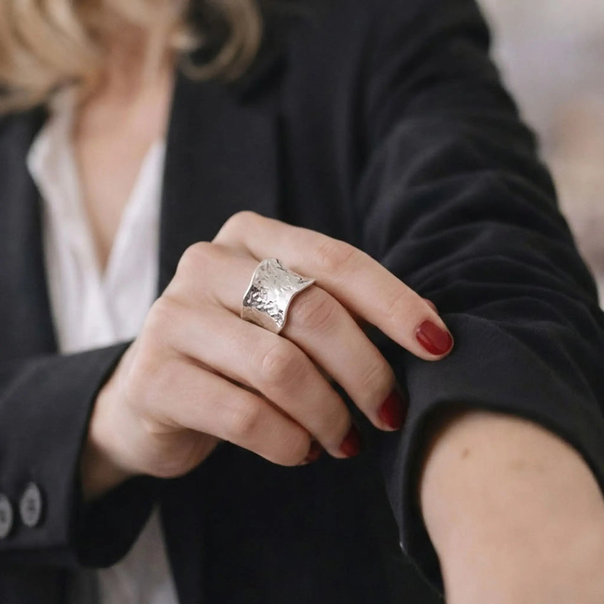 Eleganter Damenring Silber breit strukturiert getragen zum schwarzen Business-Blazer.