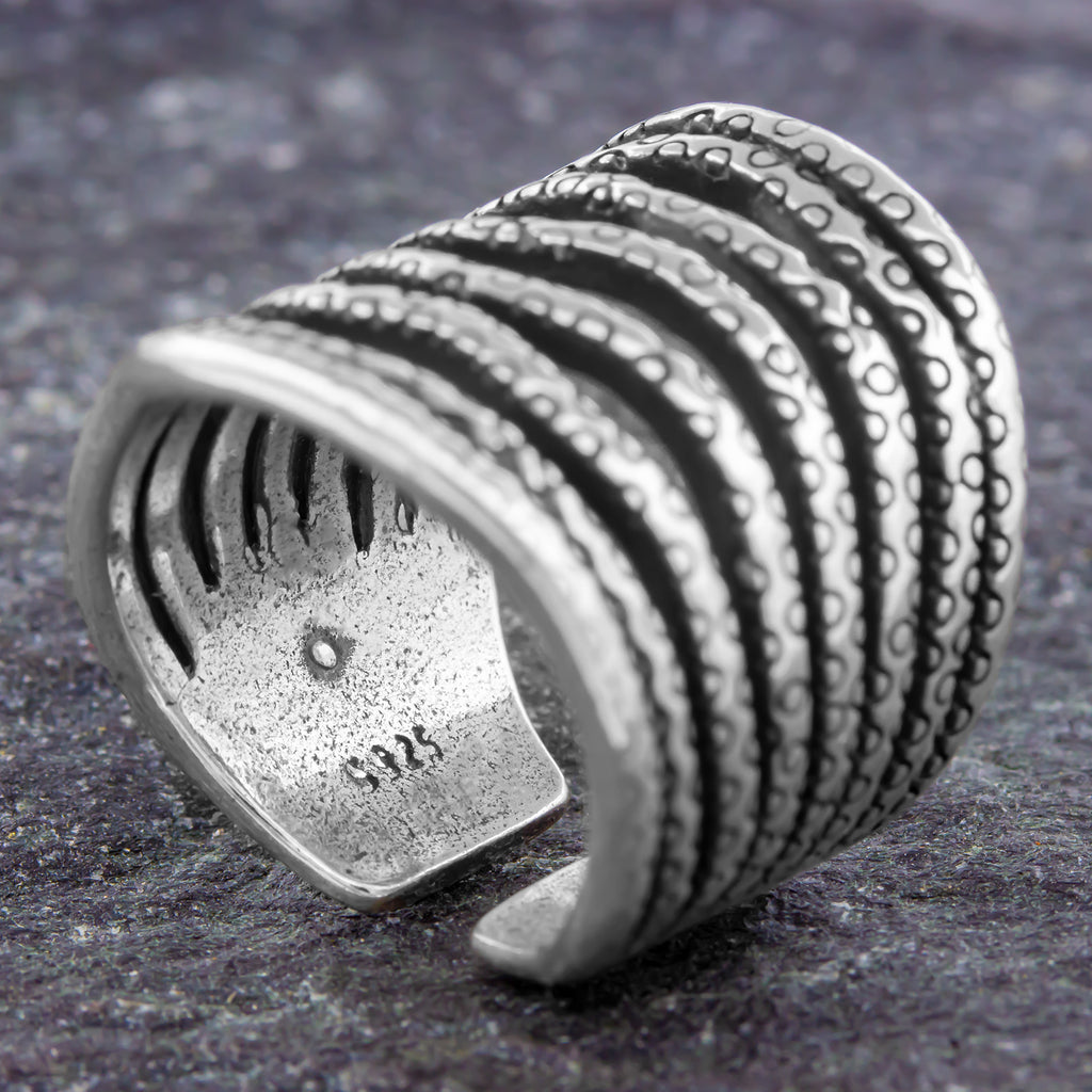 Verstellbarer Silberring 925 offen mit breitem Ringkopf, strukturierter Wellenform und dekorativem Muster auf grauem Stein fotografiert