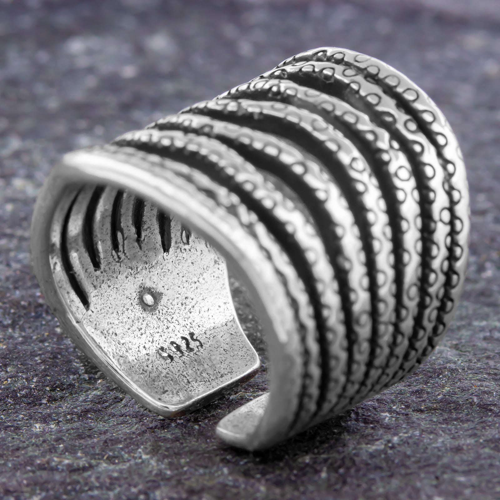 Verstellbarer Silberring 925 offen mit breitem Ringkopf, strukturierter Wellenform und dekorativem Muster auf grauem Stein fotografiert
