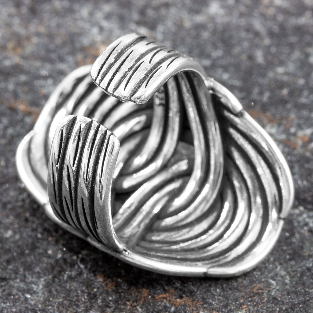 Perspektivische Ansicht von oben auf dunklem Stein, die das Spiel der geschwungenen Silberstränge und die solide Bauweise des Bandrings zeigt.