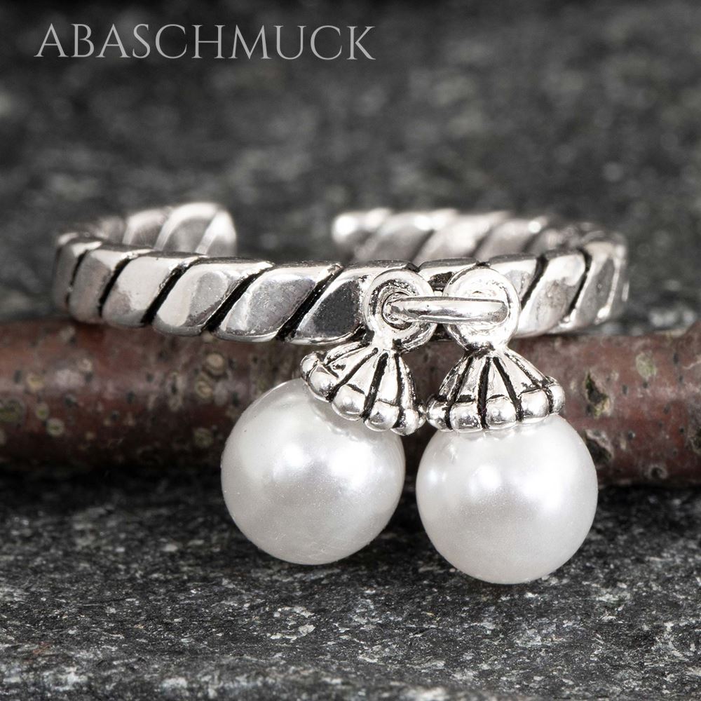 Nahaufnahme eines zarten gedrehten Silberrings 925 mit zwei Perlenanhängern.