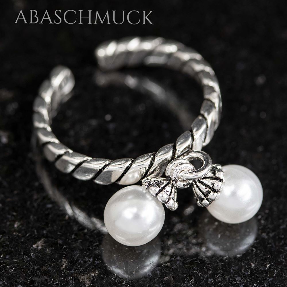 Schrägansicht eines gedrehten Silberrings mit zwei kleinen Perlen.