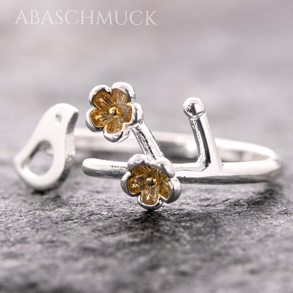 Nahaufnahme eines offenen 925-Silberrings mit kleinem Vogelmotiv und zwei goldfarbenen Blüten auf dunklem 