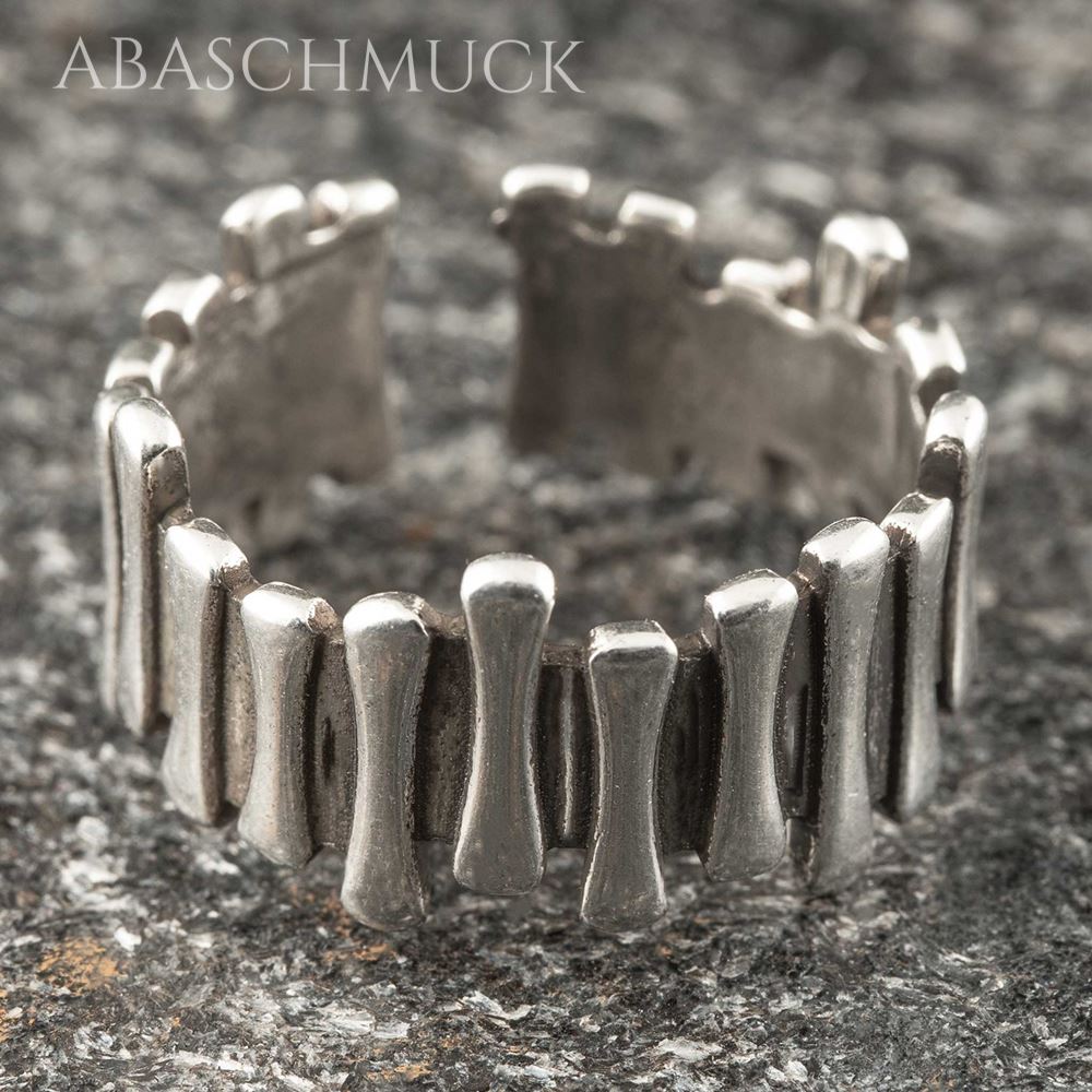 Offener Bandring aus Silber 925 mit markanten einzelnen Elementen auf Steinoberfläche.