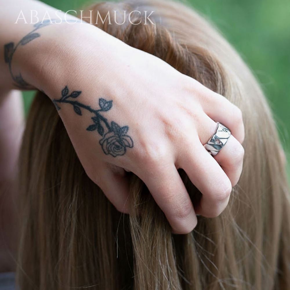 Frau trägt glänzenden geflochtenen Silberring, Hand greift ins Haar.