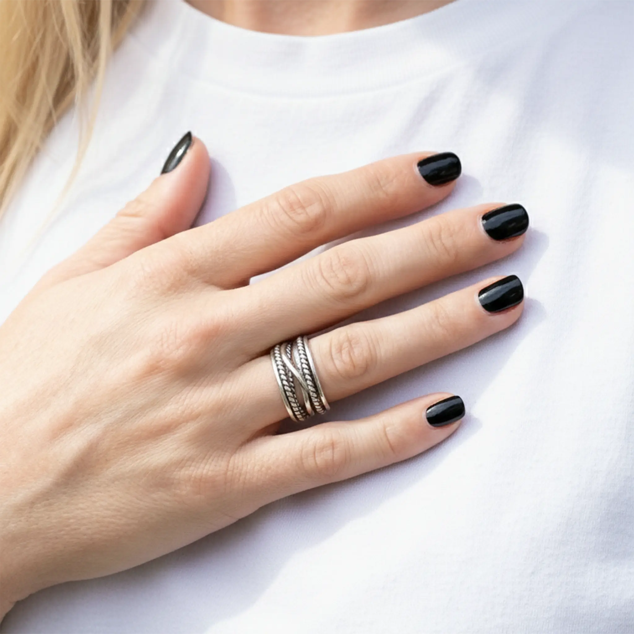 Breiter Wickelring aus 925 Silber im Ethno-Stil an Frauenhand mit schwarzen Nägeln.