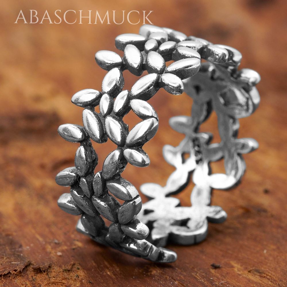 Nahaufnahme eines offenen Silberrings aus 925 Silber mit detailliertem Blättermotiv auf warmer Holzoberfläche.
