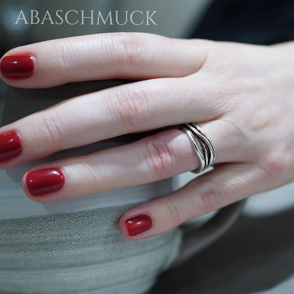 Moderner Silberring an Hand, gehalten an grauer Keramiktasse.