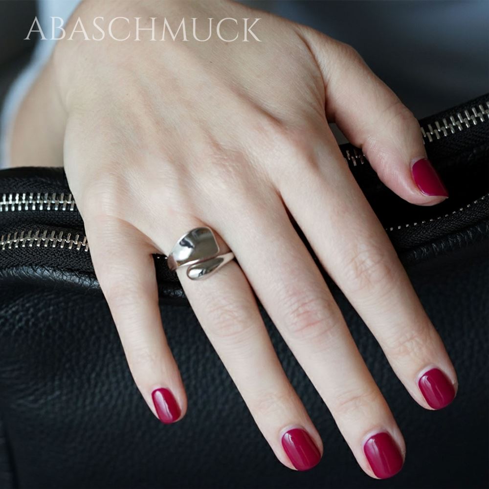 Damenhand mit modernem offenem 925 Silberring beim Halten einer schwarzen Tasche