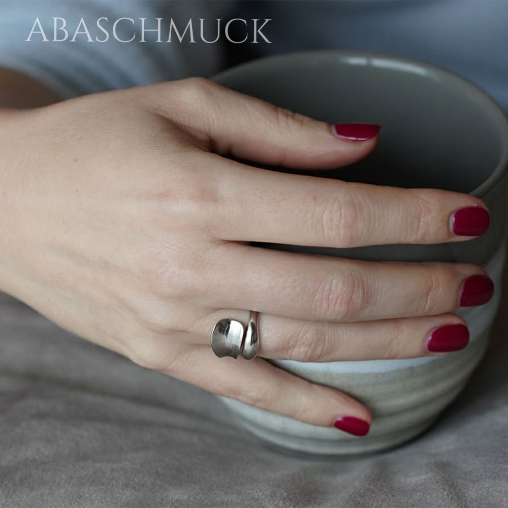 Damenhand mit elegantem, geschwungenem Silberring beim Halten einer Keramiktasse