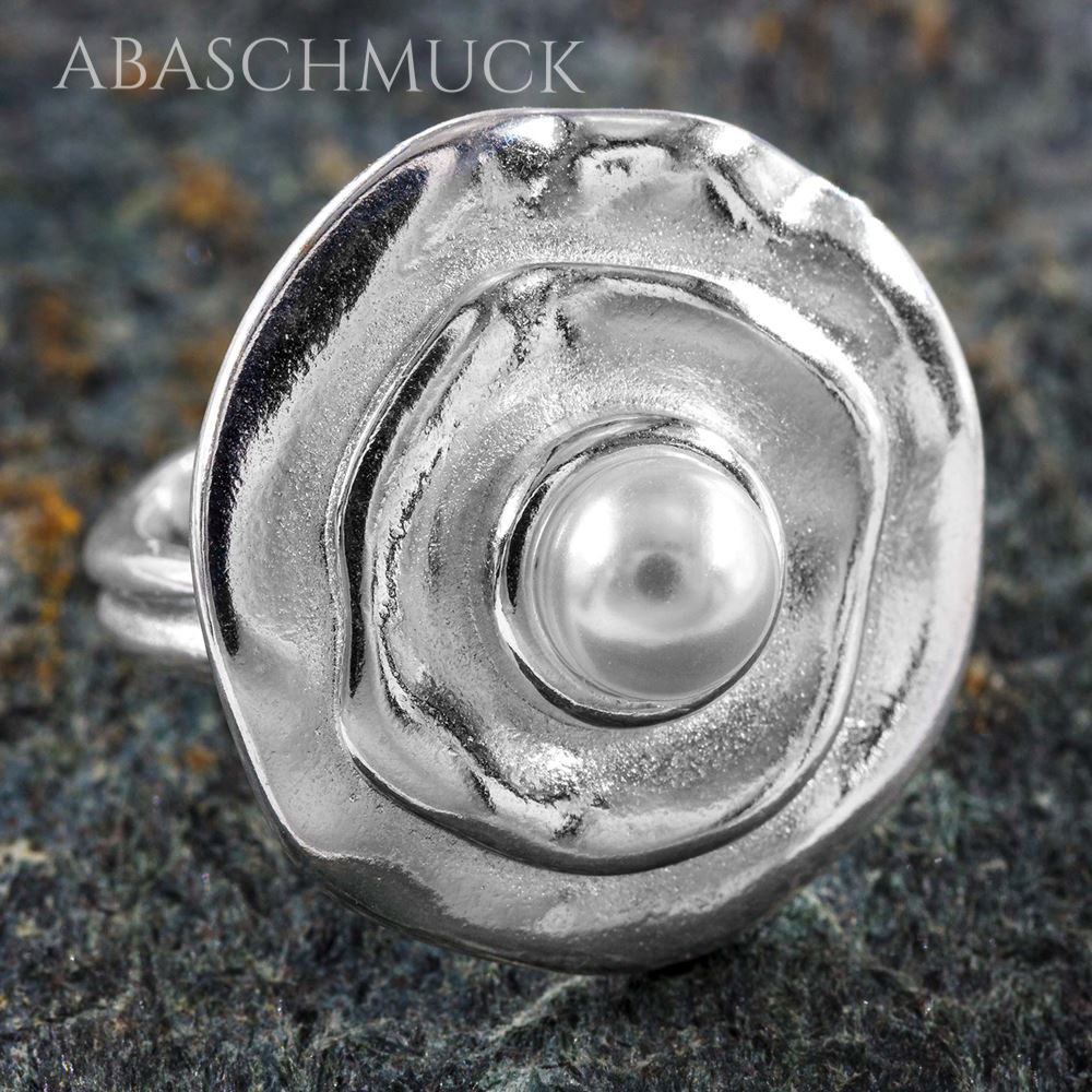 Silberring in Blütenform mit Perle in Nahaufnahme auf Steinuntergrund