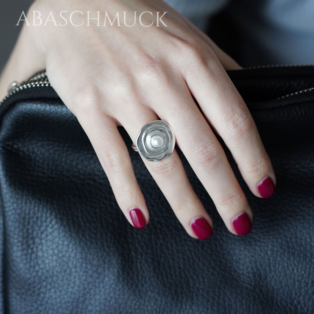 Silberner Blütenring mit Perle an der Hand, elegant präsentiert