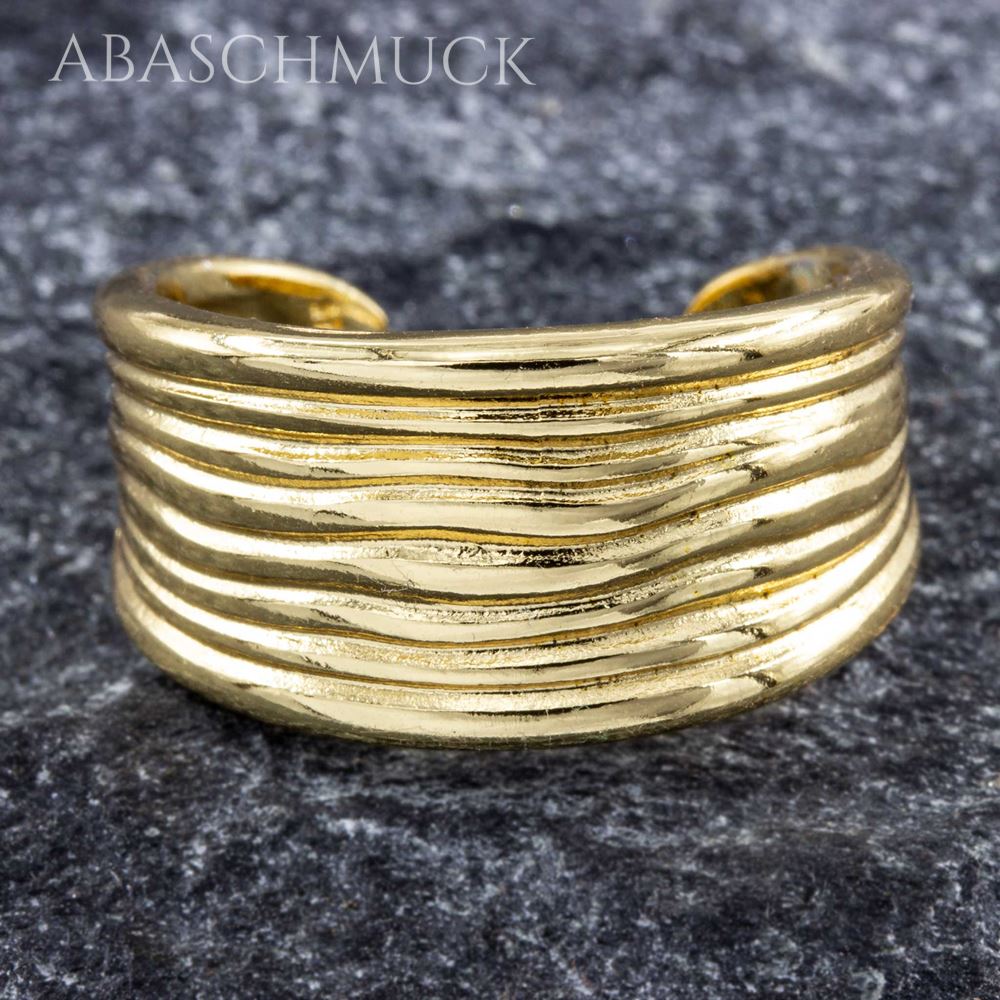 Strukturierter goldfarbener Bandring auf dunklem Steinuntergrund.