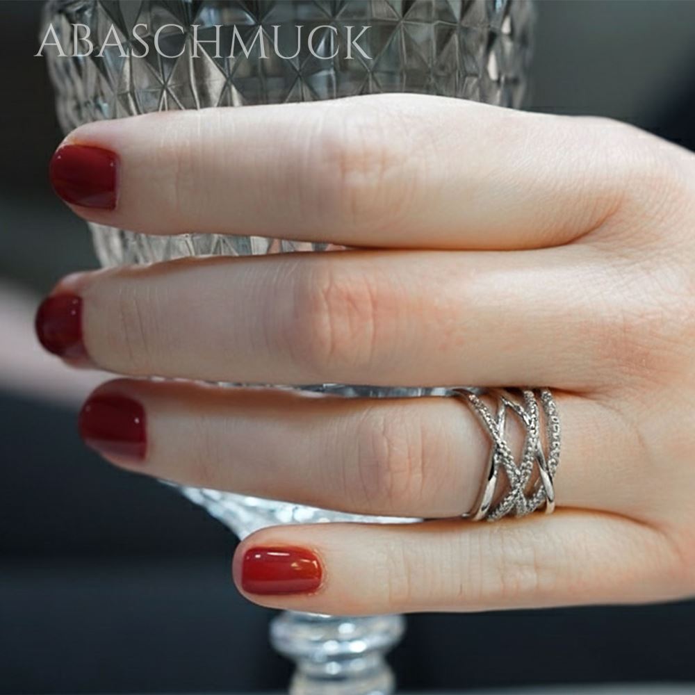 Silberring mit funkelnden, überkreuzten Elementen, getragen an der Hand.