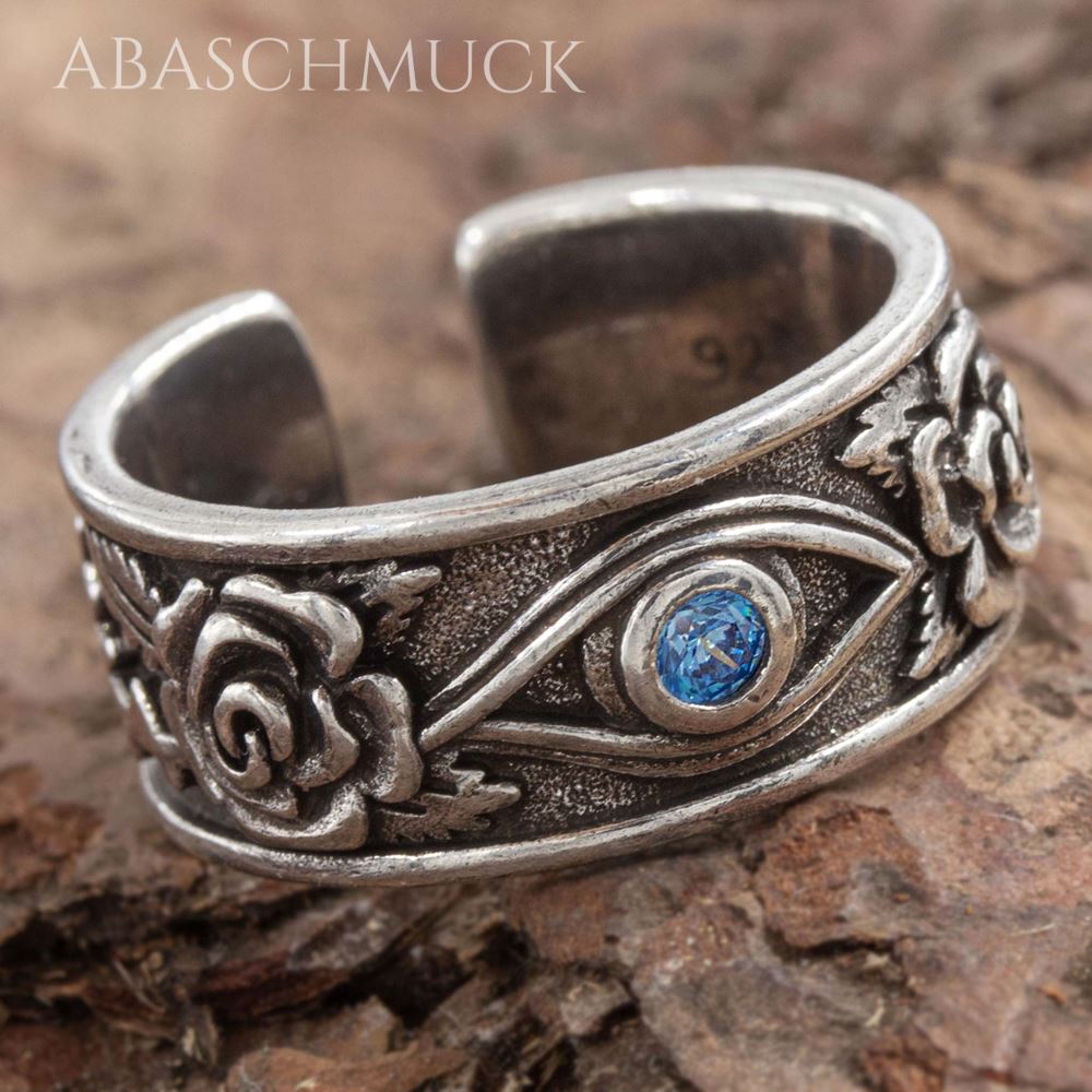 Detailaufnahme eines offenen Silberrings mit Rosenornament und blauem Stein.